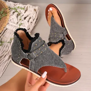 Detailed view of women's denim flat thong sandals with metal studs and back zipper