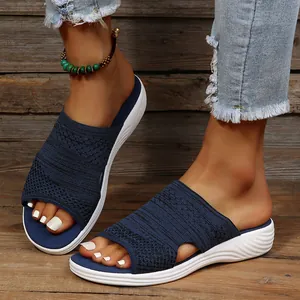 Detailed view of women's navy blue knitted summer flat sandals shown on feet outdoors.