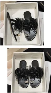 Detailansicht schwarzer flacher Sandalen mit Netzschleifen und Kristall-Zehenverzierungen