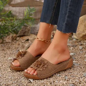 Women's brown floral wedge sandals shown on feet over outdoor gravel background