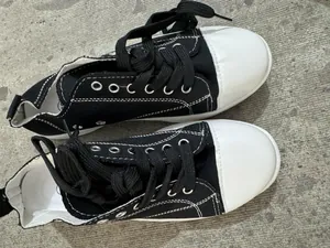 Vue de dessus de baskets en toile noire avec bouts en caoutchouc blanc et lacets