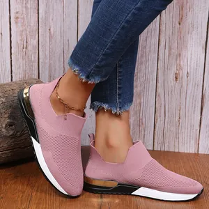 Gros plan de baskets roses respirantes en maille sur pieds avec fond en bois rustique