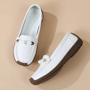 Close-up view showing the white leather texture and golden metal buckle of soft loafers