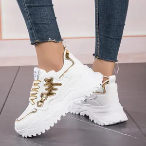 Close-up of white women's chunky sneakers with gold fishbone metallic details