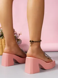 Detail view of pink platform slippers with rhinestone embellishments on clear strap.