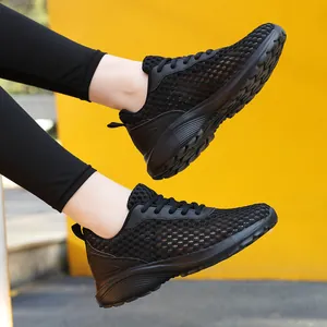 Sneaker da donna in rete nera traspirante con suola spessa su sfondo giallo brillante