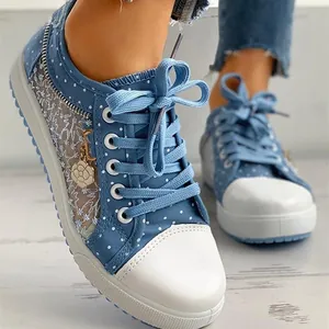 Close-up of blue polka dot canvas sneakers with breathable mesh panels and flower charm.