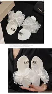 Detailansicht weißer flacher Sandalen mit eleganter Netzschleife und Strass-Zehenring-Dekor