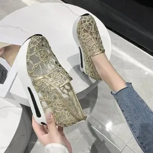 Close-up detail of women's gold mesh embroidered platform sneakers with thick white wedge soles