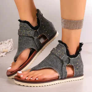 Close-up of stylish grey denim thong sandals with metal studs and back zipper detail.