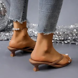 Detailed view of nude kitten heel thong sandals styled with jeans and pearl anklet