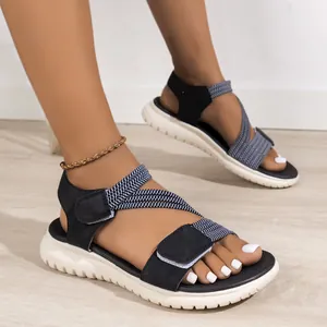 Women's blue woven strap sandals with Velcro closure and chunky white wavy soles.