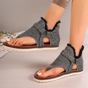 Close-up view of women's denim thong sandals featuring studs and back zipper detail