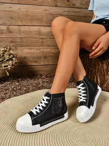 Zijaanzicht van zwarte high-top canvas platform schoenen met ritsdetail op het model