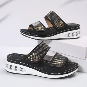 Close-up of black wedge sandals with rhinestone straps and cushioned sole