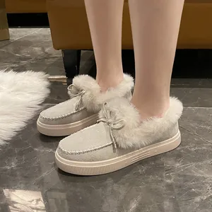 Vue détaillée de mocassins d'hiver beiges avec nœud et doublure en fourrure sur marbre.
