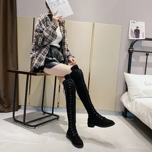 Stivali alti neri stringati indossati da una modella in una camera da letto accogliente