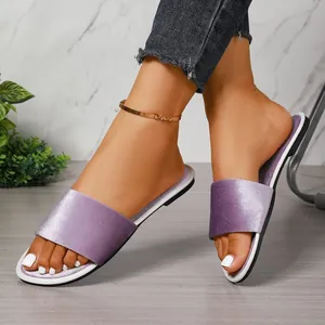 Detailed close-up shot of elegant purple velvet flat slides being worn on feet indoors
