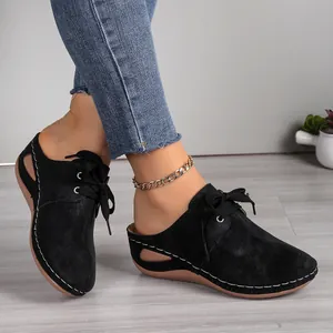 Side view of black lace-up wedge mules with hollow-out design and white stitching.