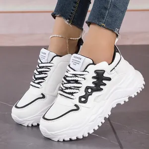 Detail view of white chunky sneakers with black fishbone design and thick soles on feet.