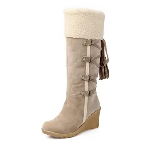 Detalle de botas de nieve de ante beige con ribete de forro polar y borlas