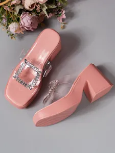 Close-up detail of pink platform slippers featuring rhinestone square buckle and clear strap