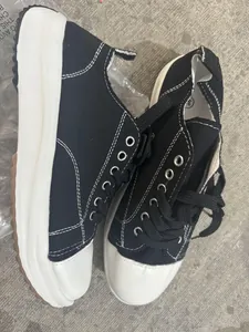 Gros plan de baskets en toile noire avec semelles blanches épaisses et coutures contrastées
