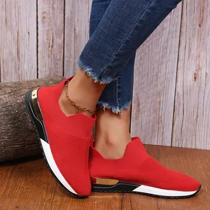 Vue détaillée de baskets en maille rouge avec accent doré au talon sur fond bois