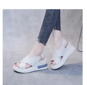 Close-up of beige platform wedge sandals with cross-straps and blue heel accent