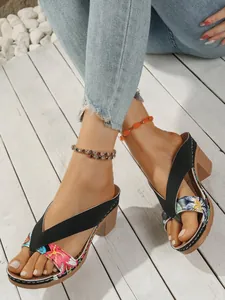 Close-up detail of women's wedge flip-flop sandals with vibrant floral straps