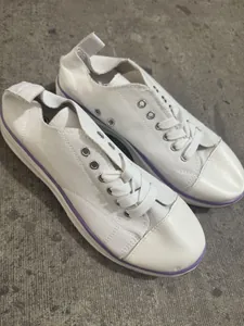 Gros plan de chaussures basses en toile blanche avec semelle violette et lacets