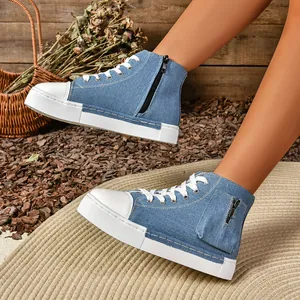 Close-up van blauwe denim hoge platform sneakers met functioneel ritsdetail aan de zijkant.