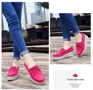 Vista detallada de mocasines con plataforma en ante rosa con borlas en cubierta de madera.