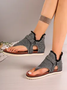 Detailed view of women's flat denim thong sandals featuring gold studs and frayed edges