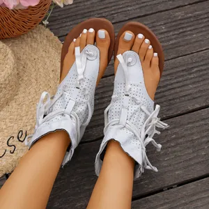 Primer plano de sandalias blancas de estilo bohemio con cordones en suelo de madera