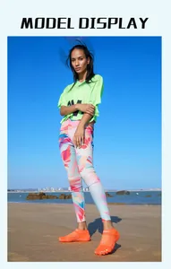 Model wearing orange five-finger water shoes on a sunny beach detail view