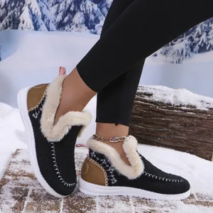 Close-up of stylish black warm winter moccasin shoes with plush fur lining in the snow