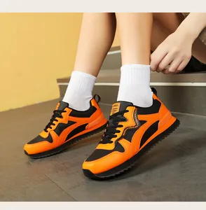 Detail view of stylish retro orange and black sneakers worn by a model on indoor stairs
