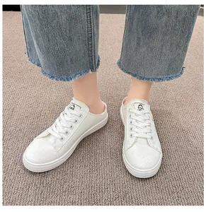 Primer plano de zapatillas mules de lona blanca para mujer con vaqueros desflecados