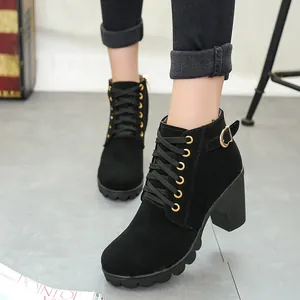 Detail of black suede ankle boots with block heel, gold buckle, and lace-up front