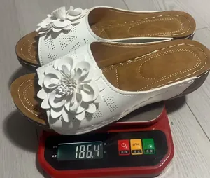 Vista detallada de sandalias de cuña blancas con flores pesadas en báscula a 186,4 g