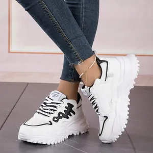 Detailed view of white chunky sneakers with black fishbone pattern and mesh