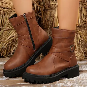 Retro brown women's combat boots with buckle detail shown on a rustic straw background