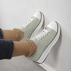 Détail de baskets en toile à plateforme vert clair avec bout rond blanc et lacets