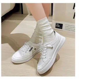 Dettaglio di sneaker bianche piatte retrò con lacci e calzini a coste beige.