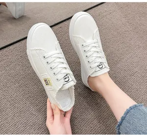 Vista detallada de elegantes zapatillas mule de lona blanca con diseño de cordones bajos