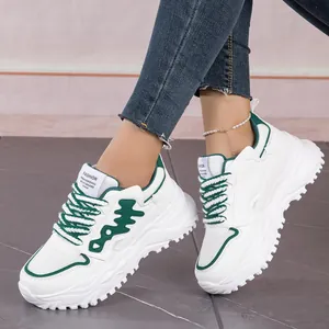 Side view of white and green breathable mesh chunky sneakers worn with blue jeans.