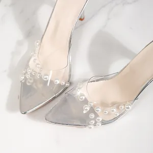 Close-up of elegant pearl decorations on transparent pointed-toe high heel sandals.