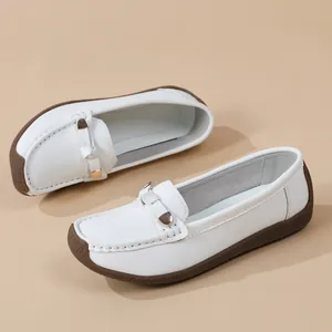 Detailed view of white women's moccasins with soft brown sole and metal buckle