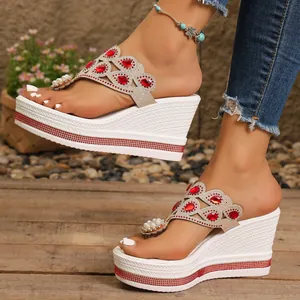 Detalle de sandalias blancas de cuña con pedrería roja y perlas en primer plano